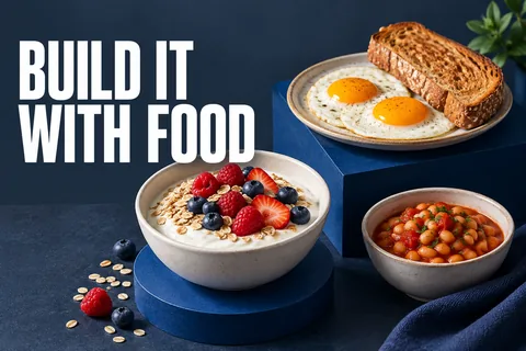 英語の BUILD IT WITH FOOD という文字の横に、ヨーグルト、卵、豆、トースト、果物を置いたアイボリー色の朝食トレー。